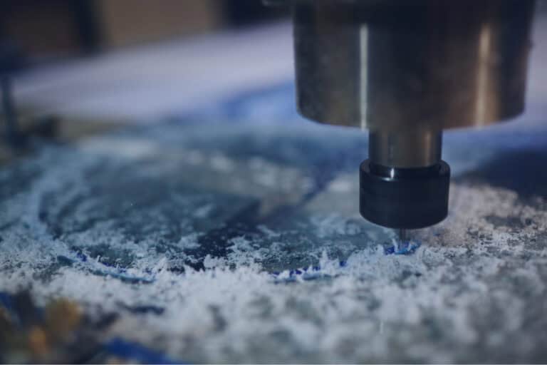 Gros plan d'une machine-outil à commande numérique par héliogravure qui découpe ou grave un matériau, entourée de copeaux. La scène met en valeur le fraisage de précision.