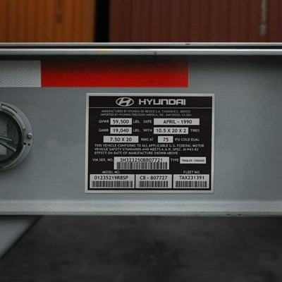 Gros plan d'une étiquette d'information sur un véhicule Hyundai affichant des spécifications telles que la date de fabrication, les limites de poids, la taille des pneus et les numéros d'identification sur une surface métallique.