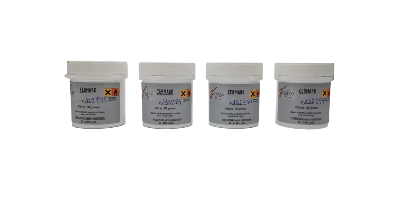 Quatre contenants blancs de céramique dentaire CERAMAX de Jensen Dental sont alignés. Chacun porte une étiquette grise avec « K32 S99 » en bleu et un symbole davertissement, conformément aux directives standard de marquage des produits. Les contenants sont cylindriques avec des couvercles blancs.