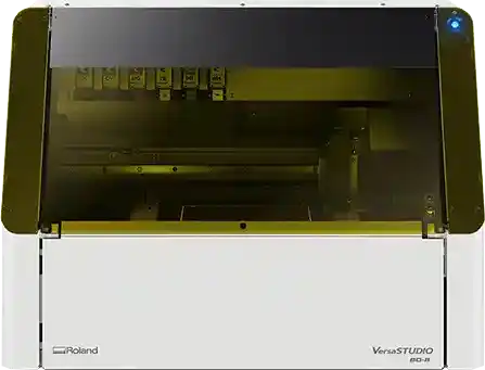 Une imprimante Roland VersaSTUDIO au design épuré, dotée dun capot transparent dévoilant ses composants internes, offre une interface numérique pour améliorer lexpérience *impression objet*.