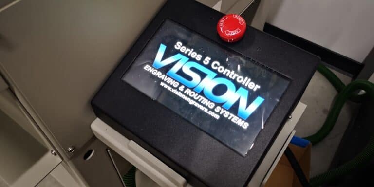 Gros plan dun contrôleur Vison Series 5 pour systèmes de gravure et de routage, idéal pour le fraisage moyen format. Un bouton darrêt durgence rouge orne le dessus du boîtier de contrôleur noir élégant.