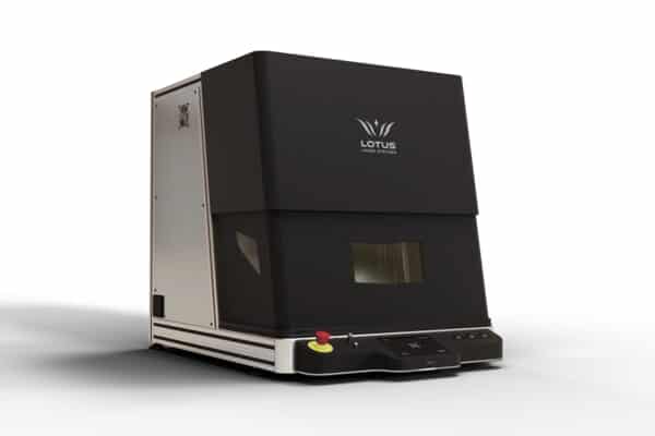 Une machine de gravure laser à fibre compacte avec un capot noir et une petite fenêtre transparente. La machine est dotée dun panneau de commande avec des boutons, dont un bouton darrêt durgence rouge bien visible. Le nom de la marque « Lotus » est visible sur le dessus, mettant en valeur la technologie MOPA avancée.