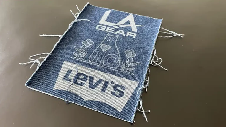 Un patch en denim parfait pour la personnalisation textile, avec « LA Gear » en haut, une forme géométrique avec des fleurs au centre et « Levis » en bas. Les bords effilochés ajoutent du caractère à sa surface unie.