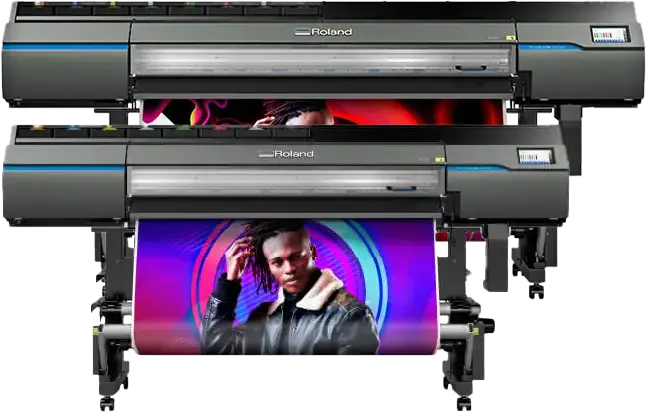 Deux grandes machines Roland imprimante/découpeuse jet d'encre sont présentées, l'une devant l'autre. L'imprimante avant imprime une affiche colorée avec une personne en veste sombre posant devant un fond circulaire vibrant.