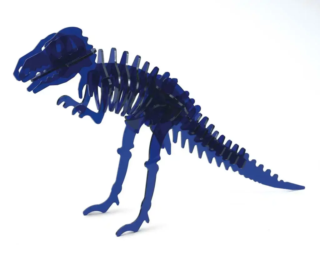 Un puzzle de dinosaure bleu en 3D, rappelant un squelette de T-Rex, est assemblé de manière experte à partir de pièces en acrylique. Ses composants incurvés façonnent le corps, les pattes et la queue sur un fond blanc simple.