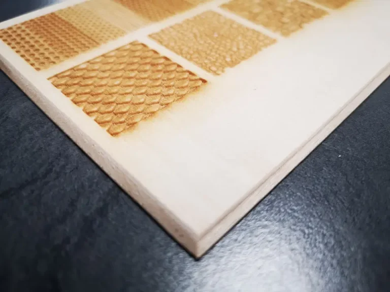 Gros plan sur une planche en bois clair, fabriquée avec précision à l'aide d'une biseauteuse, comportant de petits carrés gravés dans un motif de grille - chaque carré présente une surface texturée ou à motif unique, reposant sur une surface sombre.