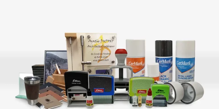 Une collection soigneusement sélectionnée pour le revendeur de machines et de matières à graver, comprenant des fournitures et équipements de bureau tels que des tampons polyvalents, des bombes aérosols CerMark, un certificat encadré, des cahiers élégants et une tasse de voyage. Les articles sont soigneusement présentés sur un fond uni.