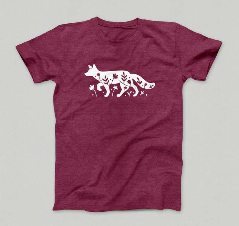 Un t-shirt bordeau présente une silhouette blanche d'un renard marchant gracieusement parmi les feuilles et les plantes, réalisée avec précision à laide dun traceur de découpe pour des détails complexes.