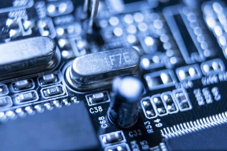 Gros plan d'un circuit imprimé bleu comportant divers composants électroniques, dont des condensateurs et des résistances.