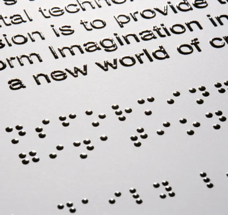 Gros plan d'une page comportant à la fois des points de braille en relief et du texte anglais imprimé, grâce à une imprimante sur objet. Le braille apparaît directement sous les mots imprimés correspondants, ce qui permet de lire les informations au toucher ou à la vue.