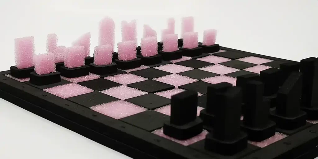 Un échiquier avec des pièces en mousse découpé au laser sur un damier noir et rose. Les pièces, fabriquées avec une précision de découpe au laser, sont de forme abstraite et géométrique, créant un look moderne et artistique.