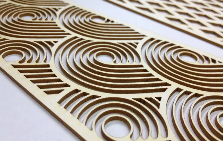Gros plan de panneaux en bois découpés au laser aux motifs circulaires et géométriques complexes, rappelant la découpe et la gravure de papier de haute précision. Le design met en valeur les couches et la profondeur, avec des arcs répétés et des cercles concentriques qui créent une texture visuellement attrayante sur un fond clair.