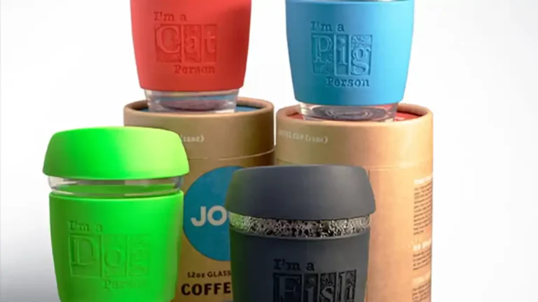Quatre tasses à café colorées avec couvercle sont présentées, chacune indiquant une préférence animale différente : « Chat », « Cochon », « Chien » et « Poisson ». Le marquage du silicone sur chaque tasse renforce leur attrait unique, le tout sur un fond neutre au-dessus dun emballage cylindrique en carton.