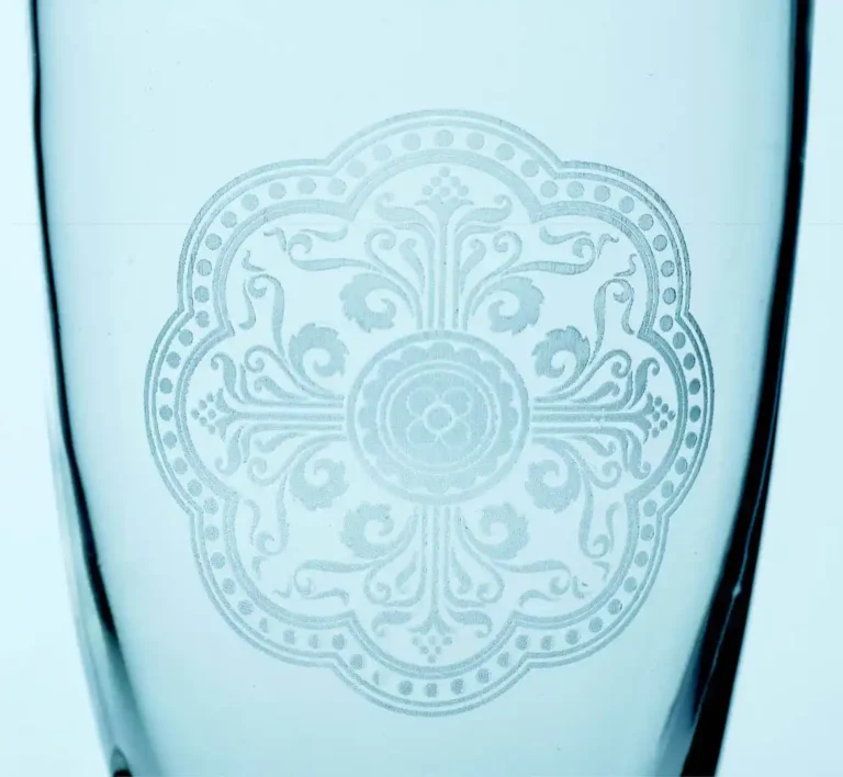 Gros plan dun verre transparent avec un motif gravé complexe, comportant des motifs floraux symétriques et des détails ornementaux centrés dans une forme ronde. Le motif gravé aux UV ajoute de la profondeur et de lélégance à lapparence générale.