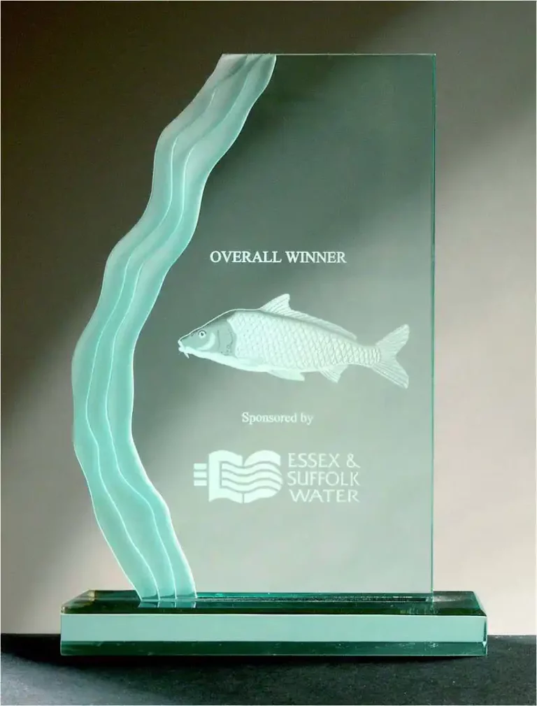 Un trophée en verre avec un motif ondulé sur le côté gauche présente un poisson gravé à laide de la gravure verre UV. Il comporte le texte « Overall Winner », ainsi que « Sponsorisé par Essex & Suffolk Water » et leur logo, sur une base rectangulaire.