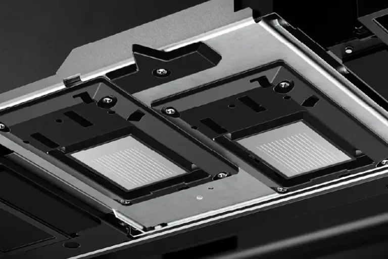Vue rapprochée de deux fentes rectangulaires pour lecteur de disque dur avec connecteurs exposés, montées sur un panneau métallique à l'intérieur d'un appareil électronique, probablement un châssis de serveur ou d'ordinateur, avec de l'espace à proximité pour une imprimante sur objet.