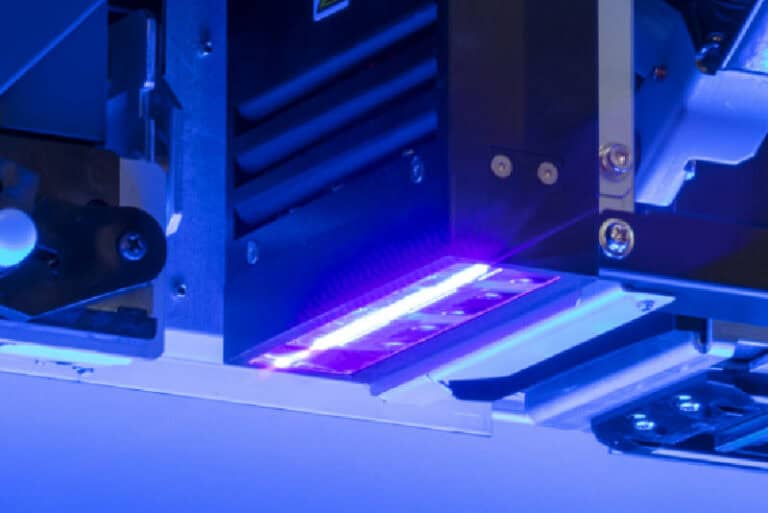Gros plan sur une machine industrielle avec des lumières LED bleues et violettes, créant limpression dun objet dart. Léquipement est composé de composants et de vis en métal, les lumières renforçant son ambiance futuriste et technologique.