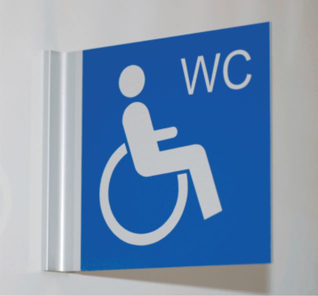 Un panneau de toilettes bleu avec un symbole de fauteuil roulant blanc indiquant laccessibilité. Les lettres « WC » sont affichées dans le coin supérieur droit.