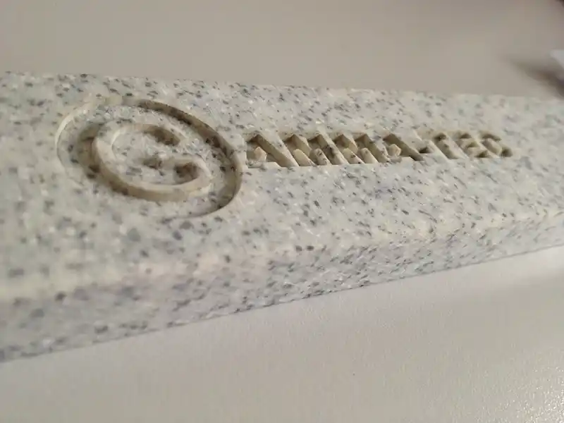 Gros plan dune dalle de pierre texturée avec un symbole de droit dauteur gravé suivi du mot « ANIMATEC ». Larrière-plan est une surface unie, mettant en valeur la gravure détaillée sur la pierre.