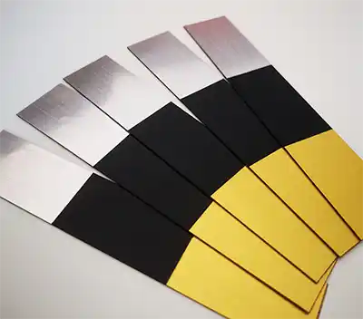 Cinq bandes rectangulaires de test de pH sont disposées en éventail sur une surface blanche. Chaque bande comporte une partie argentée, une partie noire et une partie jaune.