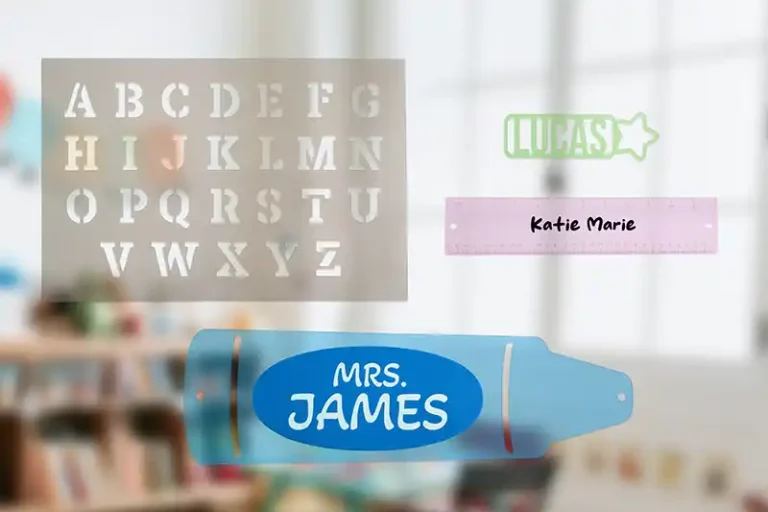 Un arrière-plan flou dune salle de classe avec un pochoir affichant des lettres majuscules, une plaque signalétique avec « LUCAS », une règle étiquetée « Katie Marie » et une étiquette nominative bleue indiquant « MME JAMES ».