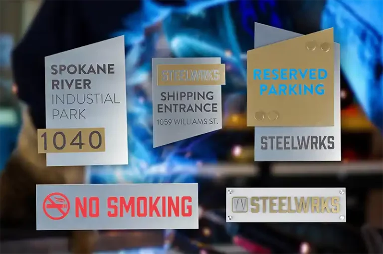 Image montrant divers panneaux industriels : « Spokane River Industrial Park 1040 », « Steelwrks Shipping Entrance 1059 Williams St. », « Reserved Parking Steelwrks », « No Smoking » et un logo « Steelwrks ». Larrière-plan comprend des machines floues.