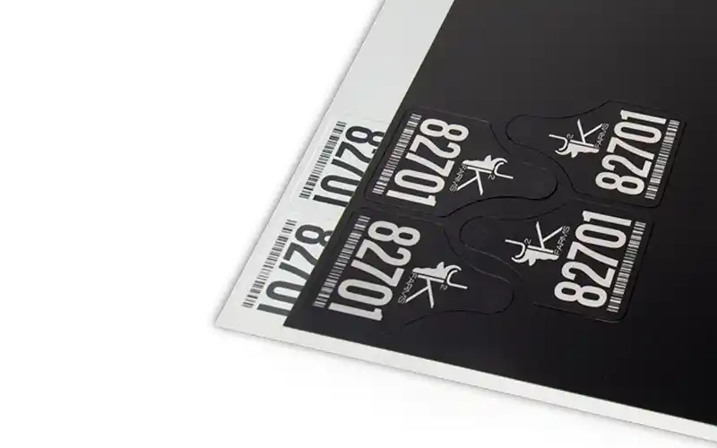 Gros plan sur des étiquettes sur fond noir. Les étiquettes comportent le numéro 82701 et une icône.