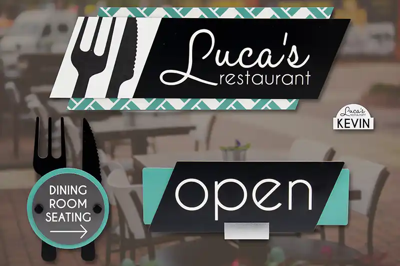 Panneau de restaurant avec le nom « Lucas » représentant une fourchette et un couteau. Comprend un panneau plus petit indiquant « Dining Room Seating » avec une flèche et un autre panneau indiquant « open » en lettres grasses sur une terrasse.