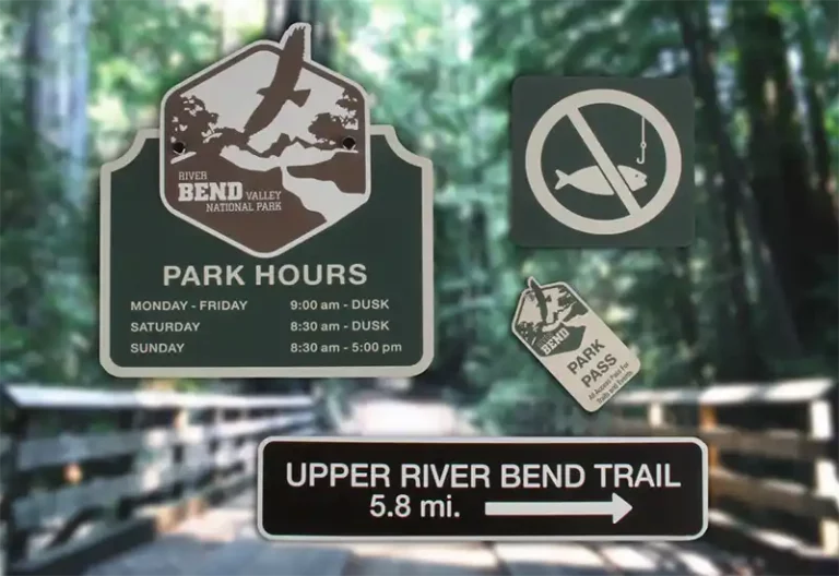 Des panneaux à lentrée dun parc indiquent les heures douverture du parc, un symbole dinterdiction de pêche, un avis de pass obligatoire pour le parc et une direction du sentier Upper River Bend, 5,8 miles. Larrière-plan présente une vue floue dun sentier boisé.