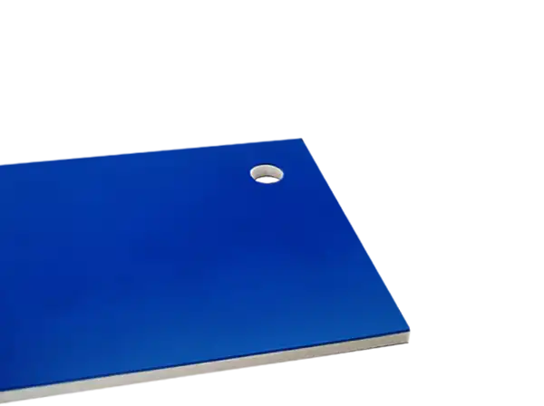 Un panneau en métal bleu, matière à graver en fraisage, présente un petit trou circulaire près du centre. Le panneau présente une surface lisse avec le trou légèrement décentré vers le haut.
