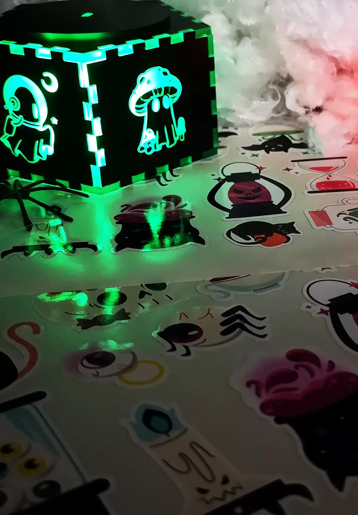 Une boîte en bois sur un lit de tissu blanc. La boîte lumineuse présente des fantômes découpés ou gravés au laser pour Halloween.