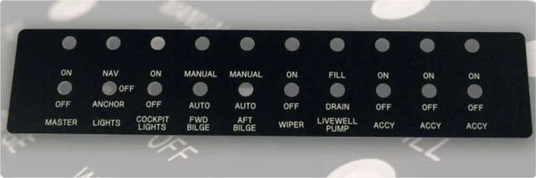 Un panneau dinterrupteurs noir avec des étiquettes blanches indiquant les différentes commandes du bateau, y compris les positions du maître-cylindre, des lumières, des lumières du cockpit, des pompes de cale, de lessuie-glace, de la pompe du vivier et des interrupteurs daccessoires. Le panneau présente une disposition en grille avec des options ON/OFF.