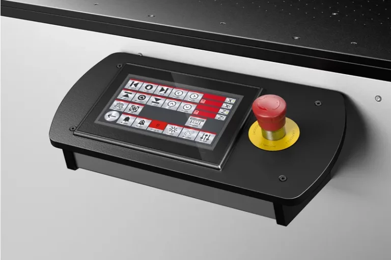 Un panneau de commande à écran tactile comportant diverses icônes et boutons est monté sur une machine à imprimer sur objet. À droite de l'écran se trouve un gros bouton d'arrêt d'urgence rouge sur une base jaune.