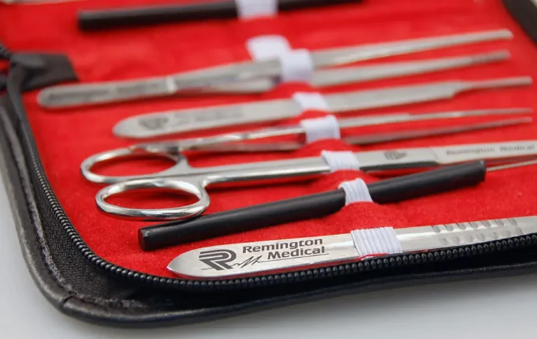 Vue rapprochée d'une mallette rouge et noire à fermeture éclair contenant des instruments chirurgicaux, notamment des ciseaux, des pinces, une pointe laser CO2 et des scalpels étiquetés Remington Medical.