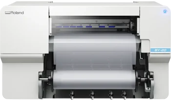 Imprimante Roland BY-20 impression DTF blanche avec un rouleau de matériau transparent partiellement chargé visible par l'ouverture avant, sur un fond uni.