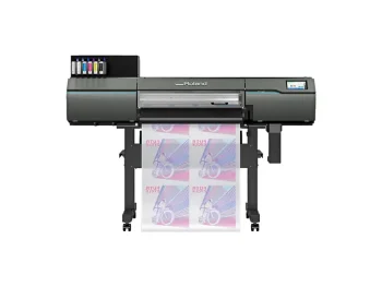 Une imprimante Roland grand format produit plusieurs feuilles d'affiches colorées avec un motif de bicyclette en utilisant la technologie d'impression DTF. Les cartouches d'encre sont visibles en haut à gauche de l'imprimante, qui repose sur quatre pieds sur un fond blanc.