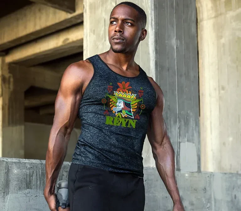Un homme vêtu d'une chemise de sport sans manche de couleur foncée avec une impression colorée DTF et le mot RAVN se tient à l'extérieur près de structures en béton, tenant une bouteille d'eau et regardant sur le côté.