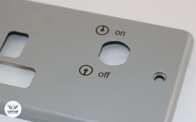 Gros plan d'un panneau métallique gris pour un marqueur laser, avec un trou circulaire étiqueté "on" en haut et "off" en bas, chacun avec des symboles de puissance. Le panneau comporte également d'autres découpes et un petit logo dans le coin inférieur gauche.