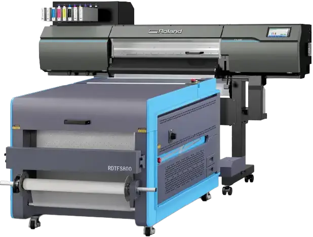 Une grande imprimante industrielle Roland avec un extérieur gris et bleu, des cartouches d'encre visibles en haut à gauche et un panneau de commande sur le côté droit. Cette machine est conçue pour les tâches d'impression DTF à haut volume.