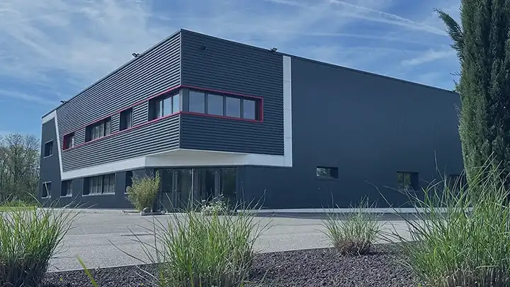 Photo extérieur des locaux de GAMMA-TEC, on y voit l'entré du bâtiment de couleur gris