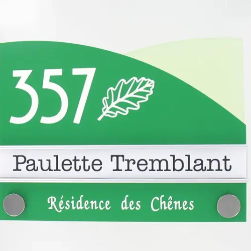 Un panneau vert et blanc affiche le numéro 357, une illustration de feuille, le nom Paulette Tremblant et le texte Résidence des Chênes, avec deux attaches métalliques aux coins inférieurs.