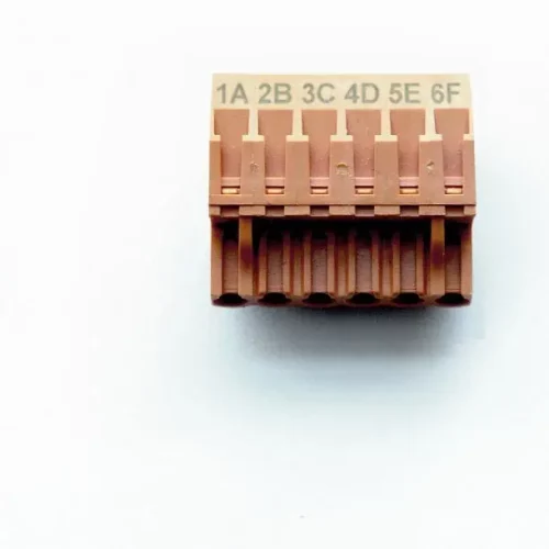 Gros plan dun bloc de connecteurs électriques marron avec six emplacements étiquetés : 1A, 2B, 3C, 4D, 5E et 6F. Le bloc est conçu de manière complexe pour une connectivité de précision, idéal pour les systèmes à fibre laser. Il est photographié sur un fond blanc uni.