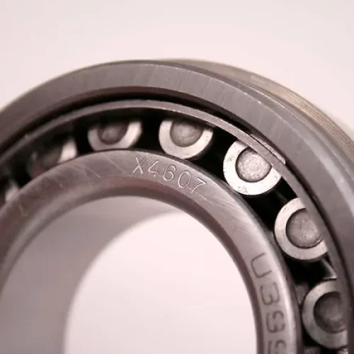 Vue rapprochée d'un roulement à billes en métal, montrant la bague, les billes qui roulent et les marques estampées sur la bague intérieure - essentielles pour les machines de fraisage en héliogravure - sur un fond uni.