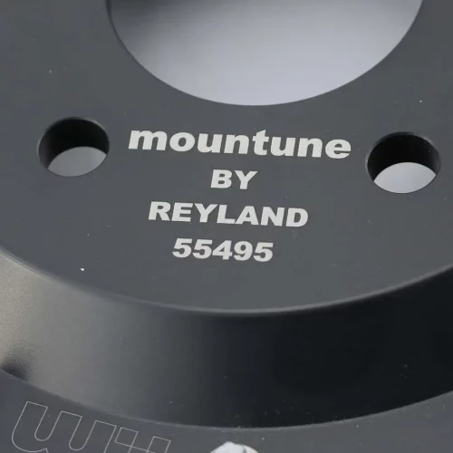 Gros plan d'une pièce automobile en métal noir avec un texte gravé en blanc - créé à l'aide d'un laser co2 marqueur - portant la mention mountune BY REYLAND 55495. Plusieurs boulons sont visibles sur le bord de la pièce.