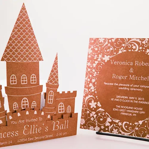 Deux cartes décoratives sont présentées : lune avec une découpe et une gravure du papier complexes, en forme de château avec le texte « Princess Ellies Ball », et une invitation de mariage à motifs floraux détaillant lévénement pour Veronica Roberts et Roger Mitchell à The Roxsand House.