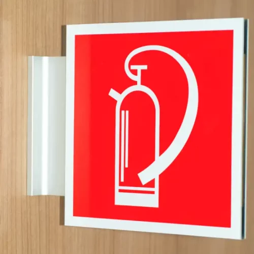 Un panneau dextincteur rouge monté sur un mur en bois, représentant la silhouette blanche dun extincteur. Le panneau a un bord saillant pour plus de visibilité.